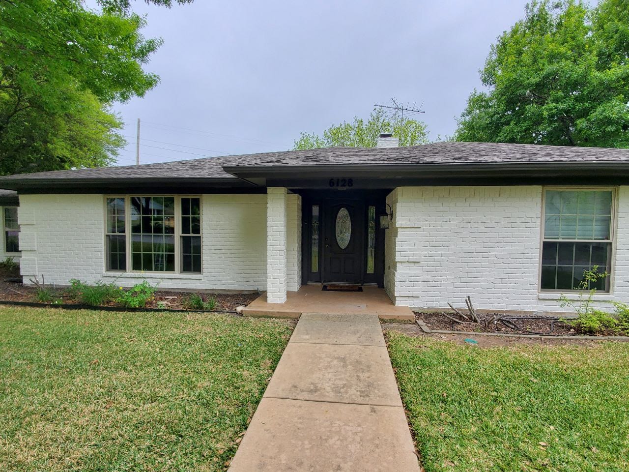 Same brick ranch home with the brick painted white and trim refreshed