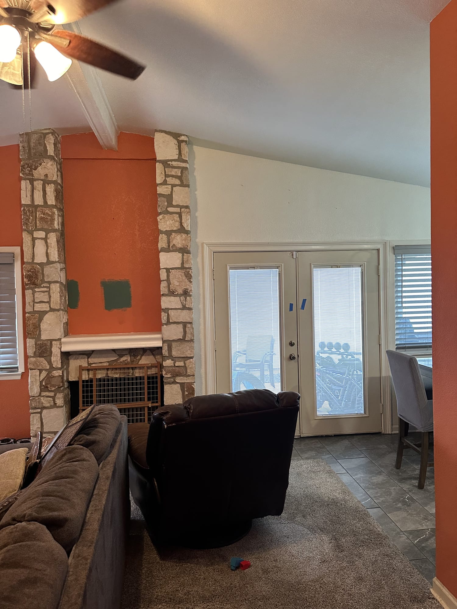 Living room with orange walls and stone fireplace before interior repainting