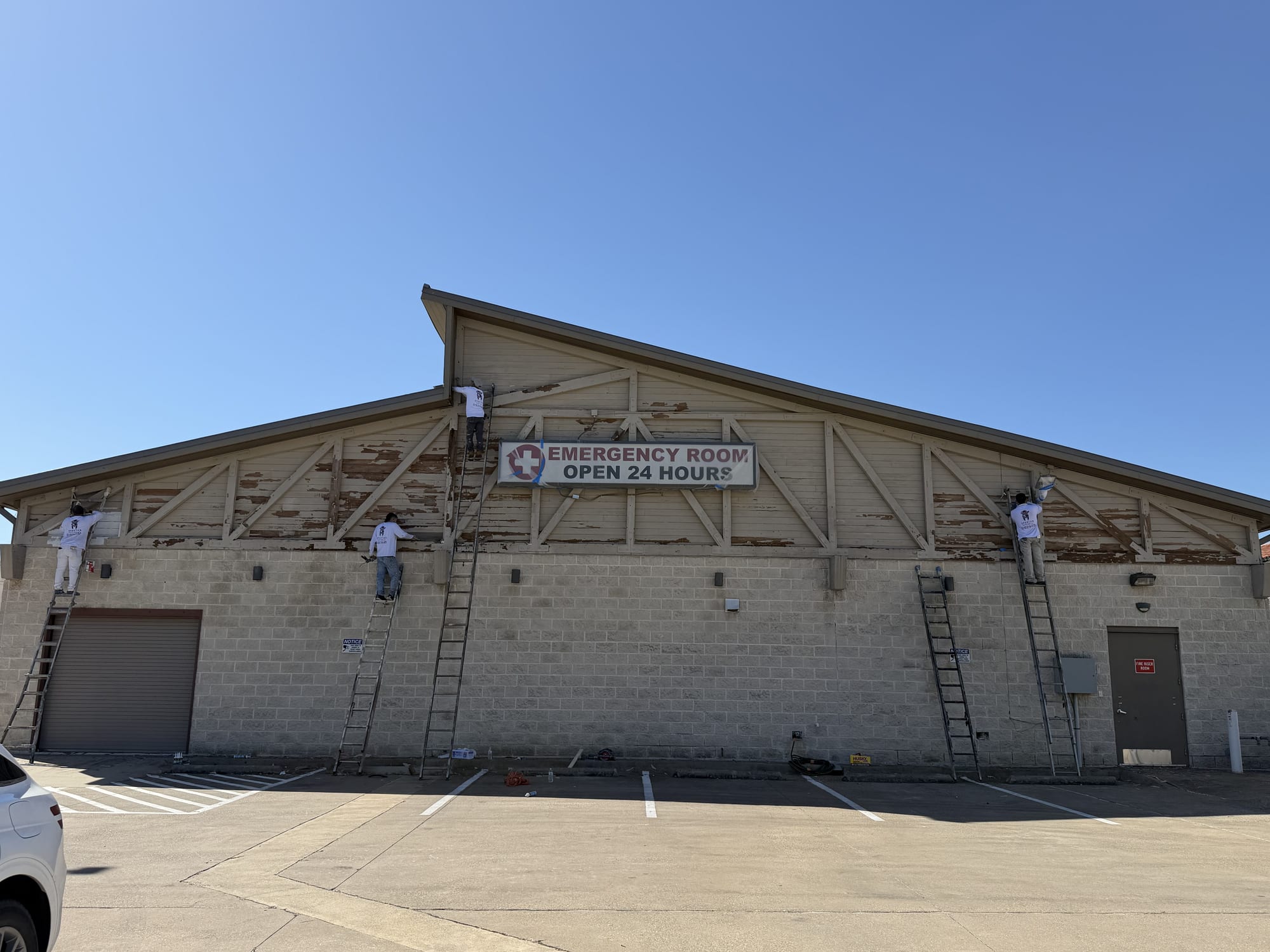 Crew on ladders prepping a commercial building exterior for repainting